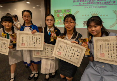 Group of five students in school uniforms pose with certificates and gold trophies at an award ceremony in a classroom.